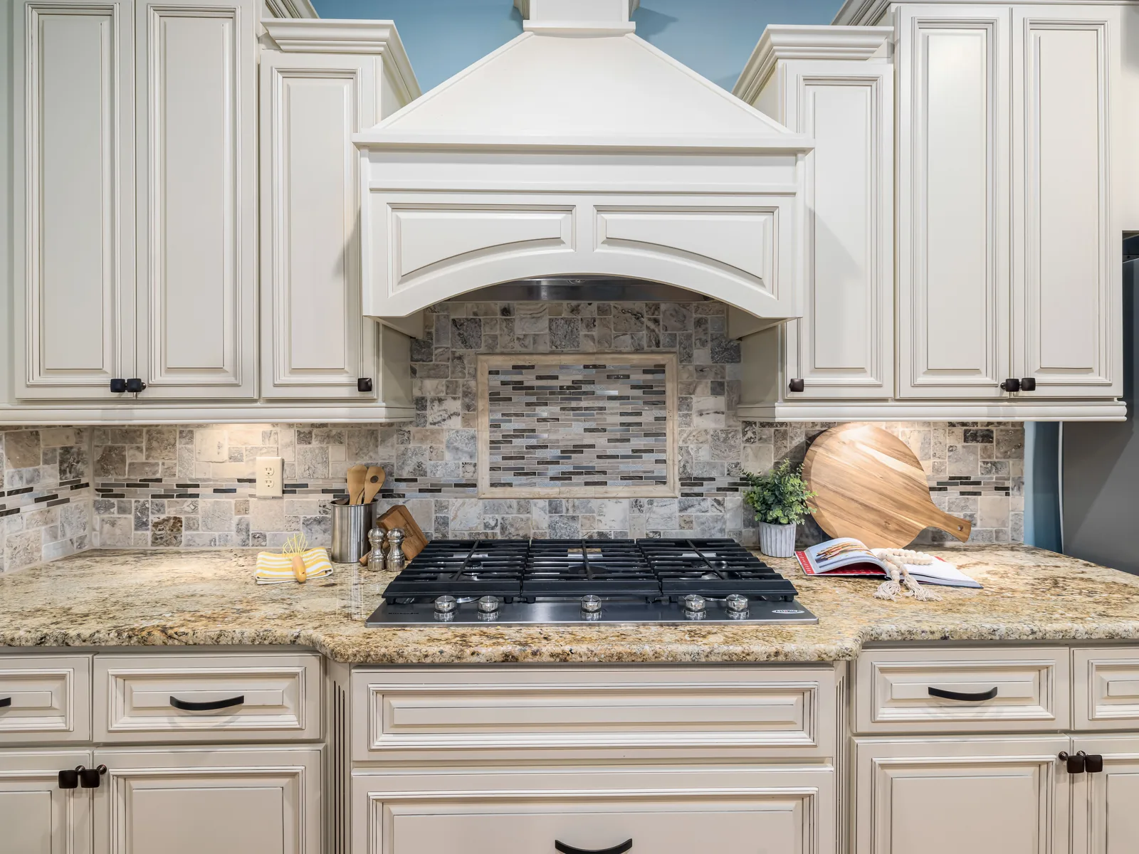Cream cabinets with stone backsplash and granite counters