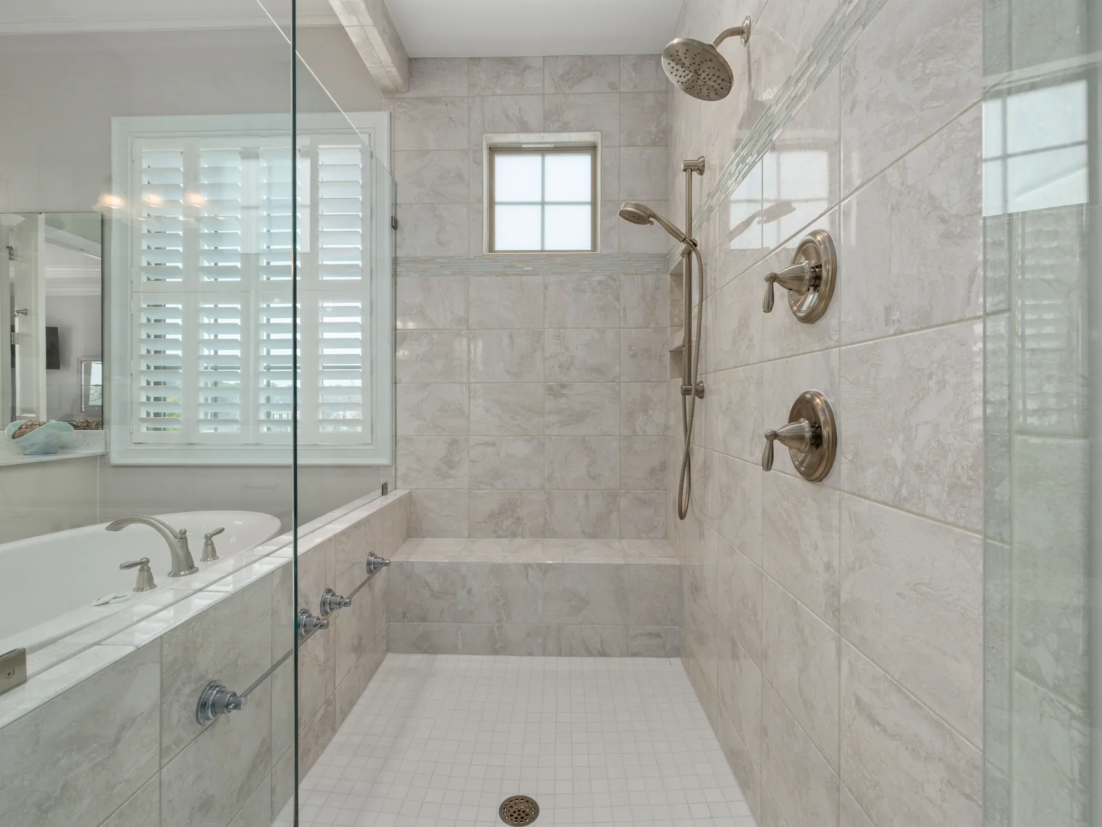 Marble walk-in shower with glass enclosure and bench
