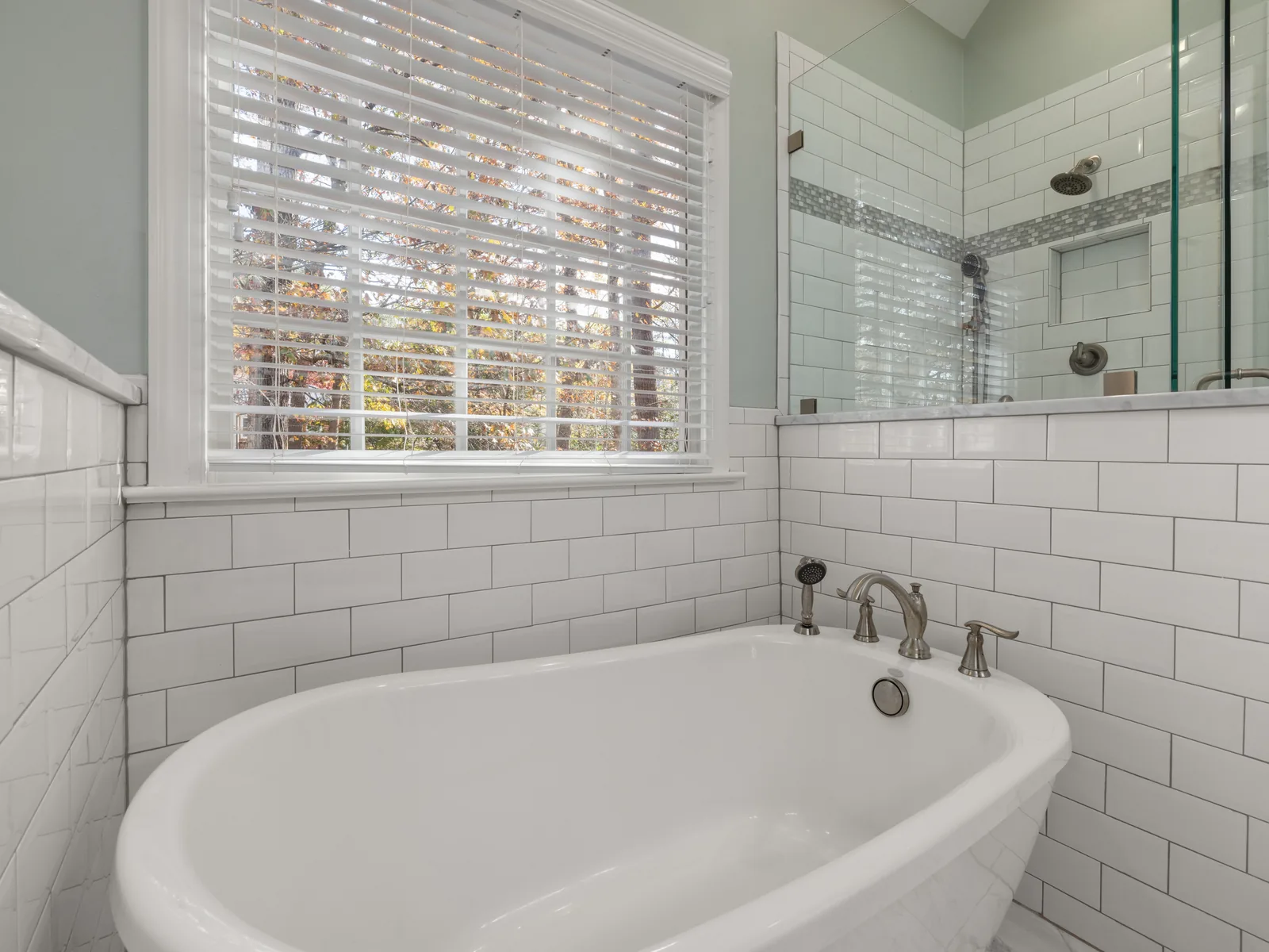 Freestanding tub against white subway tile wall