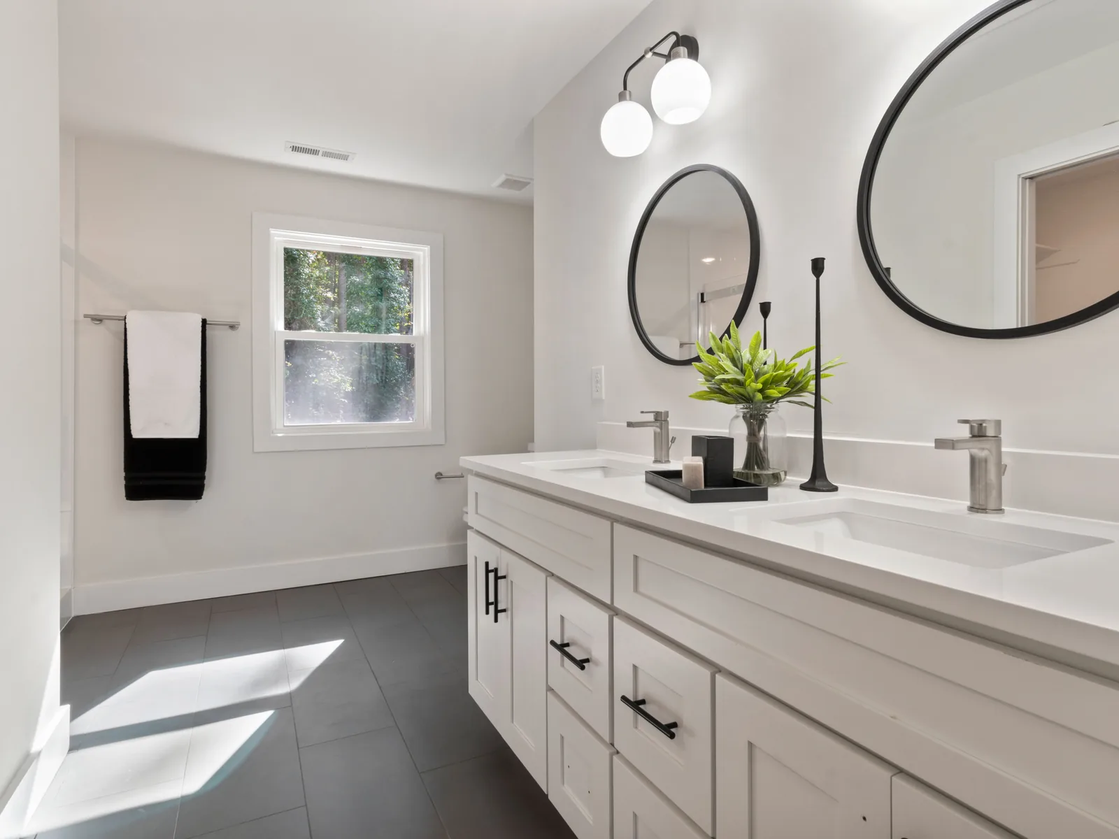 White double vanity with round mirrors and black fixtures